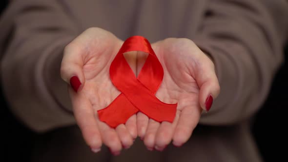Red Ribbon on Woman's Hand Support for World Aids Day.