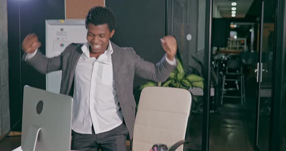African Businessman in Office in Front of Computer Showing Happy Emotions alt