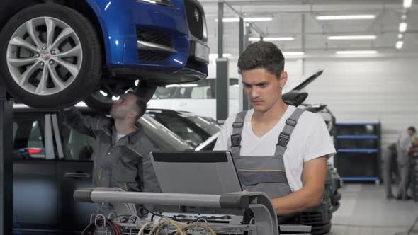 Young Car Mechanic Using Laptop at the Garage