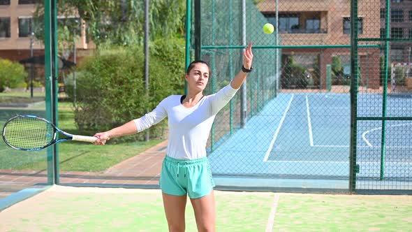 Young Woman with Long Hair Plays Tennis on the Field