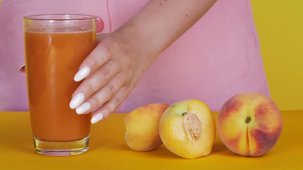 Woman Pours Juice on Fruit. Peach Juice in a Glass. Close-up.