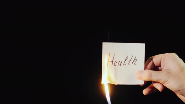 Man Burns a Paper with the Inscription Health alt