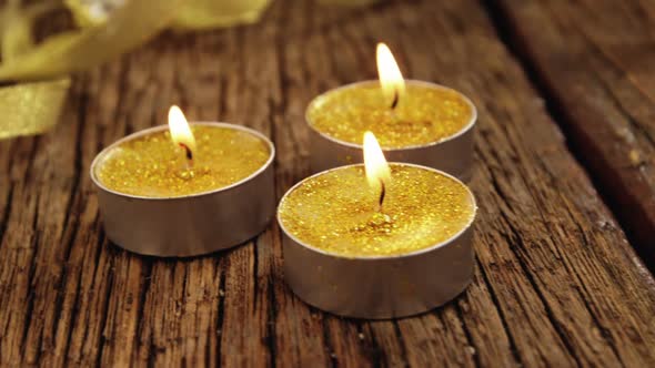 Close-up of tealight candles with glass lamps on a plank alt