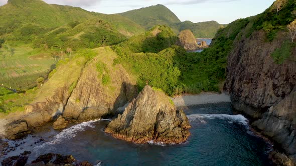 Young climber proudly standing on the steep rock elevated from the sea. Semeti hills, Bali, Indonesi alt