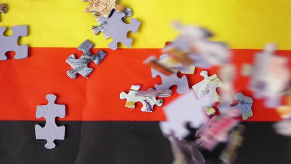 Close-up of colorful jigsaw puzzle pieces falling on the German flag in slow motion alt