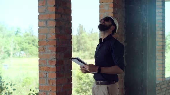 Engineer Builder In Hard Hat On Building Site. Construction Worker With Blueprints. Engineer Workman alt