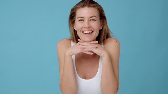 Caucasian Woman Smiling while Resting Her Face on Clasp Hands