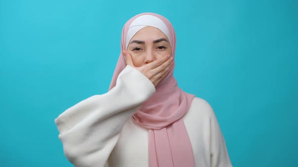Muslim Woman in Hijab Removing Hand From Her Mouth and Smiling at Camera in Studio Isolated