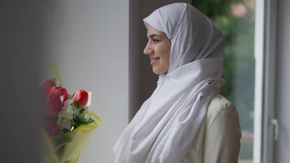 Side View Portrait of Smiling Happy Middle Eastern Bride in White Hijab Looking Out the Window alt