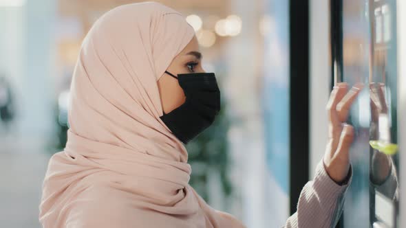 Young Arabic Woman in Protective Medical Mask Stands Near Selfservice Machine Muslim Girl Shopping alt