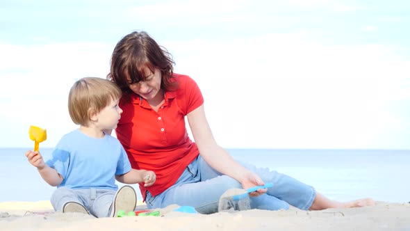 Mother Plays With Little Child On Beach alt