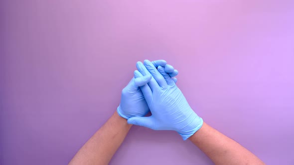 Doctor Hand with Medical Gloves Showing Support Sign on Purple Background alt