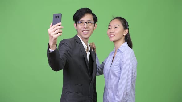 Young Asian Business Couple Using Phone Together