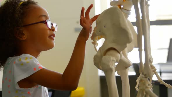 Side view of African american schoolgirl learning human skeleton in classroom at school 4k alt