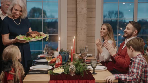 Grandmother Serves Chicken on the Table on Christmas Eve Everybody Clapping