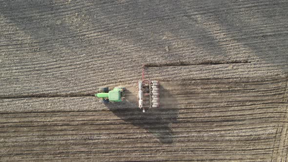 Birds eye view over tractor fertilizing and planting a farm field near the end of the day.