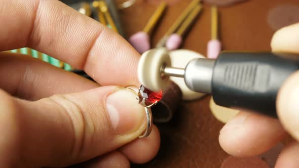 A Professional Jeweler Polishes a Red Gem on a Gold Ring Using a Special Tool alt
