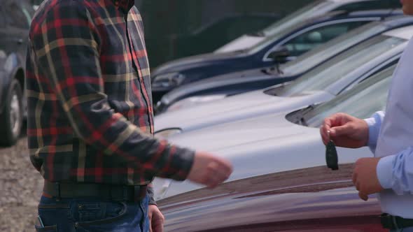 Seller of machines giving keys to buyer. Mens shaking hands each other.