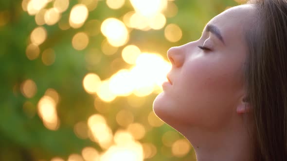 Young woman face with close eyes. Girl meditating and in contemplation with hope and faith outdoors