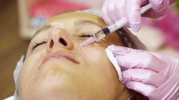 Cosmetician in Gloves Making Face Lifting Injection alt