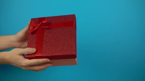 Give From Hand To Hand Present Box Holiday Gift on Color Background Celebration