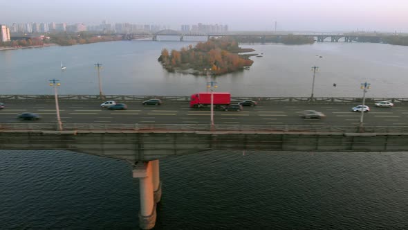 Red Truck Rides on a Road Bridge Over a River