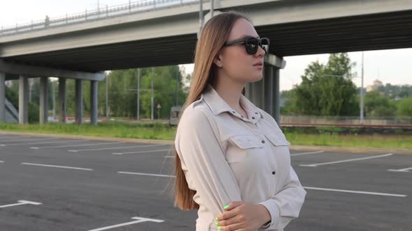 Beautiful Young Girl with Glasses Walks Through the City and Looks Around