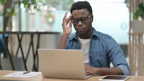 Young African Man with Headache Working on Laptop alt