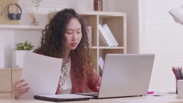 Asian designer woman uses his smartphone to communicate. Work on projects and papers. and work from alt