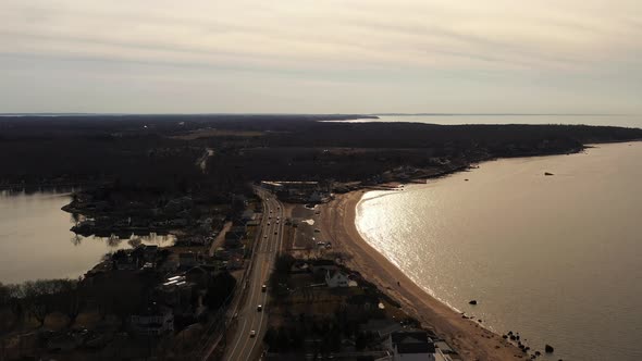 An aerial view over a narrow strip of land with an empty beach on one side, a bay and a quiet two la alt