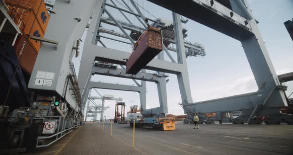 Container Cargo Lifted By a Steady Crane With the Bright Sky in the Background alt