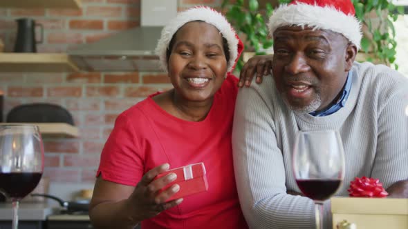 Happy african american senior couple in santa hats on video call at christmas time alt
