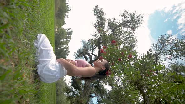 Side View of Young Woman Practicing Breath exercise Under a Tree in a Park.Vertical Yoga Video