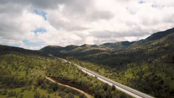 Aerial Panorama of cars driving on highway through green California mountains alt