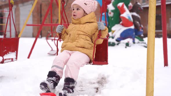 Toddler Girl Playing on Playground in Winter alt