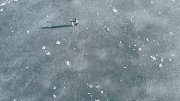 High Aerial Shot of Couple Skating on a Frozen Lake in Beautiful Sunny Landscape