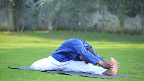 Indian man doing Folded leg forward bend yoga or Triang Mukha Eka Pada Paschimottanasana alt