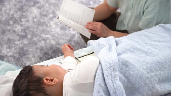 Mother reading fairy tales to her baby. alt