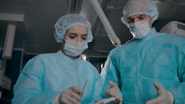 Two Surgeons in Robes Prepare Equipment for Surgery alt