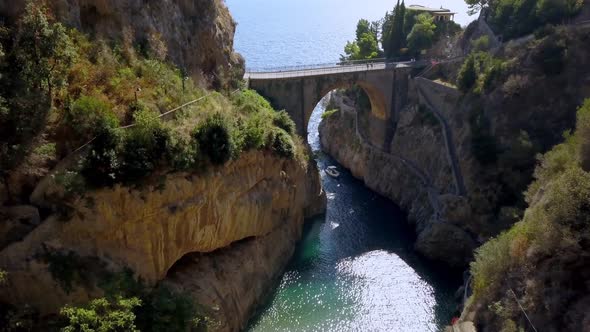 Fiordo di Furore arch bridge with a boat entering the passageway to village, Amalfi coast in Salerno alt