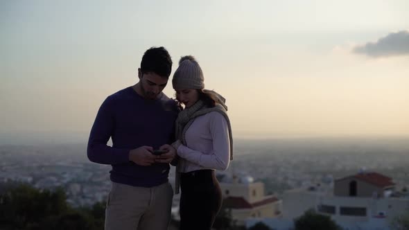 Young Multiethnic Couple Using Smartphone and Text Messaging Outdoors