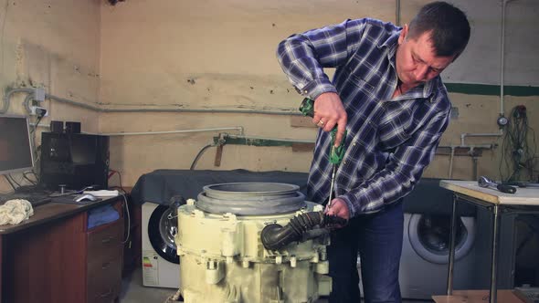 The Master Assembles the Drum of the Washing Machine Tightens the Bolts alt