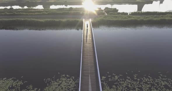 A drone shot panning down, while a girl walks on a bridge, with Dutch Windmills in the Netherlands d alt