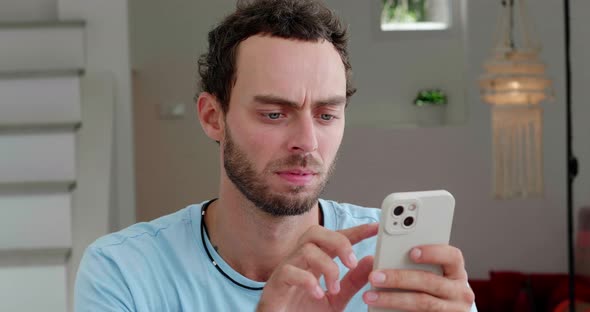 Handsome Caucasian Man in Casual Blue Tshirt Relaxing in the Home Interior Using Smartphone Types alt