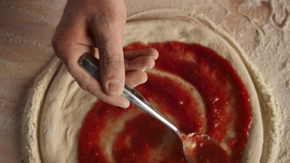 Pizza Chef Putting Ketchup Tomato Sauce on Raw Dough in Kitchen Restaurant alt