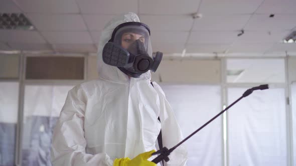 Disinfector in Special Clothes and a Protective Mask Sprays Pesticide alt