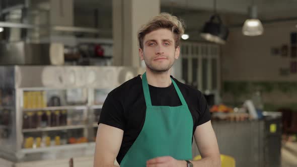 Man in Apron Keeping Hands Crossed While Posing at Cafe