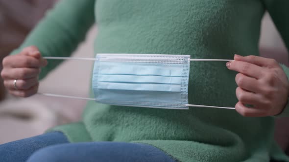 Female Hands Putting Coronavirus Face Mask on Pregnant Belly in Slow Motion alt