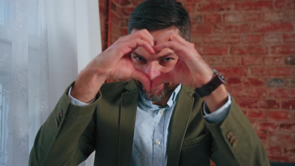 Caucasian Middleaged Man in an Elegant Jacket Doing Heart Shape with His Hands alt