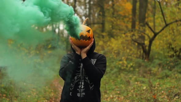 Man Holding Halloween Pumpkin in Smoke at His Head